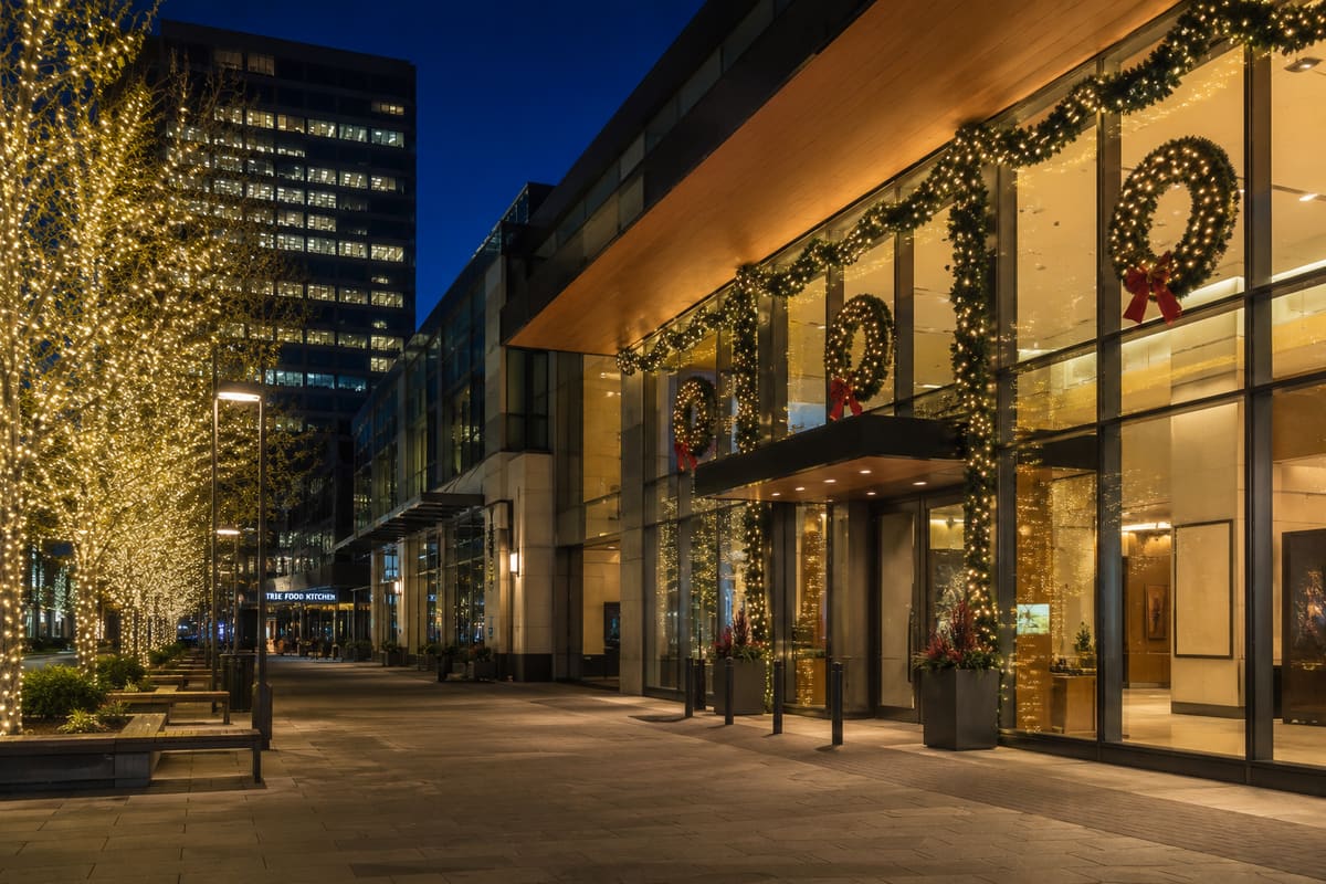A commercial plaza entrance wrapped in garland, wreaths and string-lit trees for the holidays
